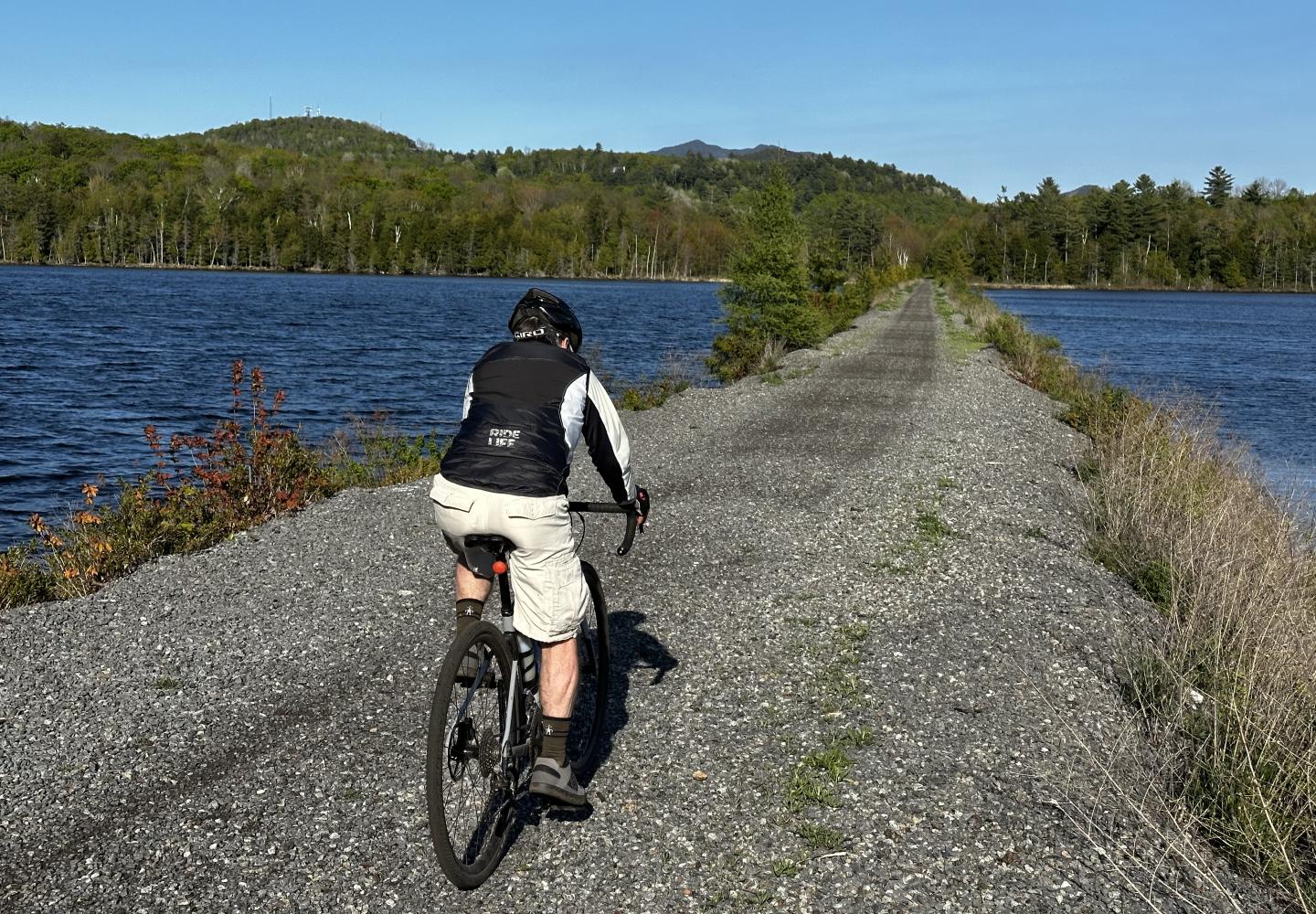 A cyclist pedals along the causeway bisecting Lake Colby.