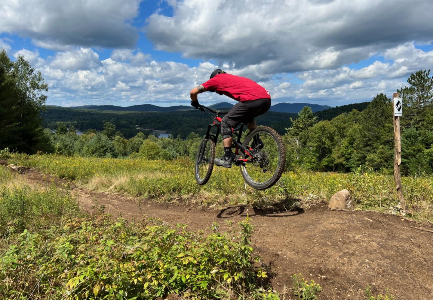 A mountain biker catches a bit of air at the top of the Paint It Black Trail on Mount Sabattis. Photo courtesy of Town of Long Lake.