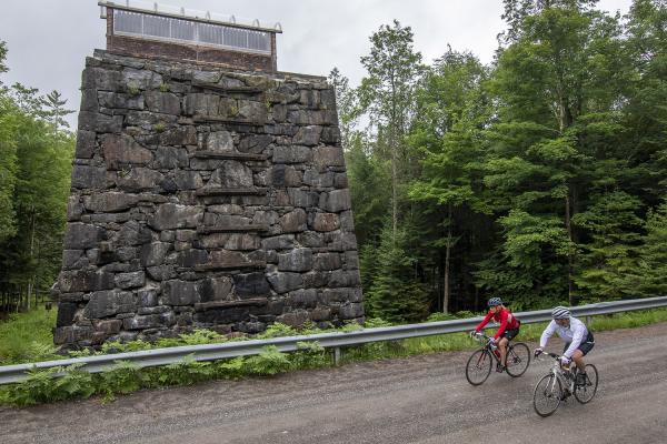 Cyclist pedal past the historic McIntyre furnace in Tahawus.
