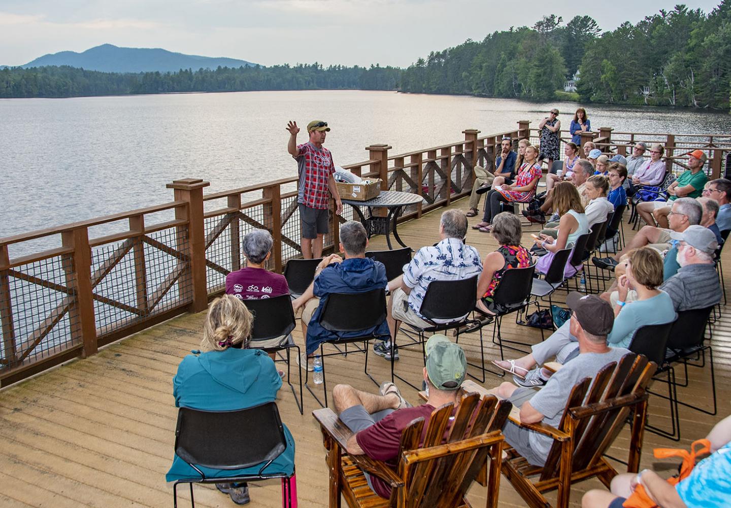 Paul Smith's College Climate Fellowship Program sharing their stories on the deck as the sun goes down over St. Regis Lake. 