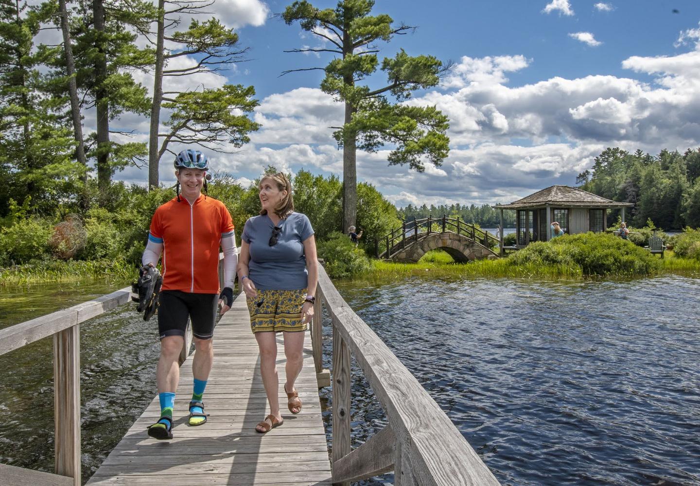 Weekender riders walk across a wooden bridge at White Pine Camp after checking out the island tea house.