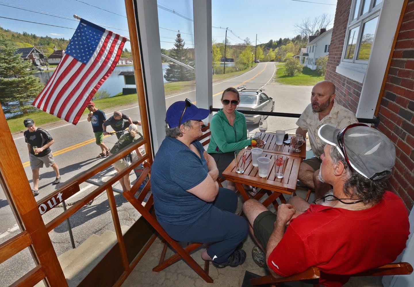 Folks enjoy the front porch dining area at the Hub overlooking Brant Lake. 