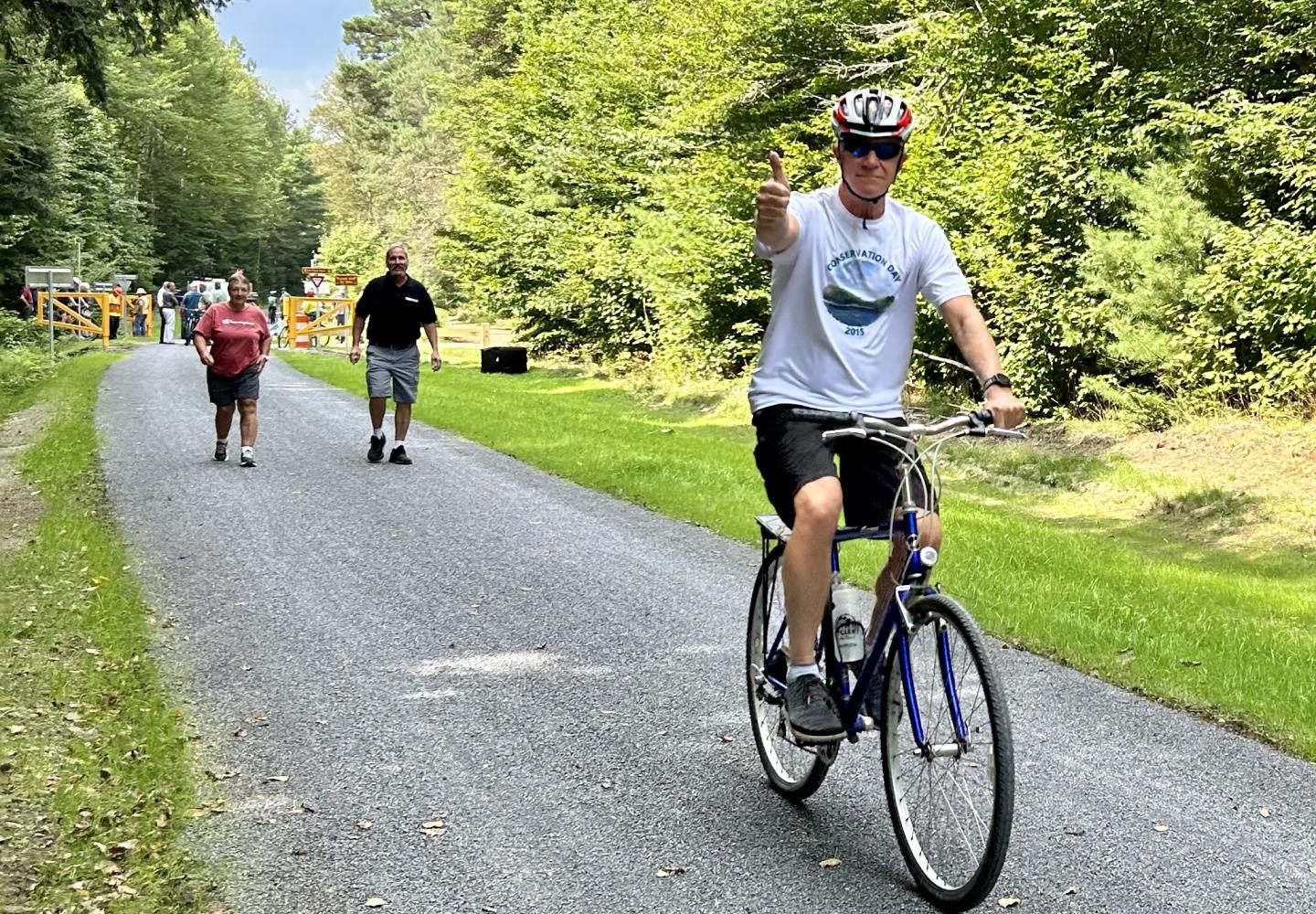 A cyclists waves to celebrate the opening of Phase 2 of the Adirondack Rail Trail.