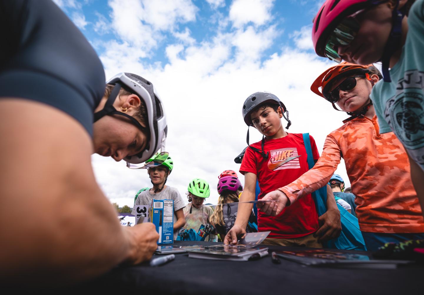 Pro riders sign autographs for young fans.