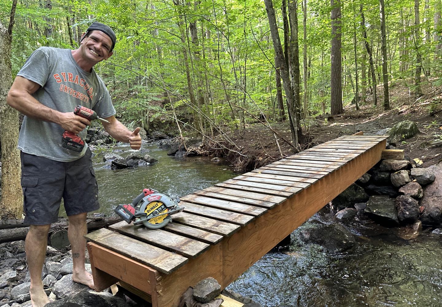 Adam Whitman, a volunteer with the St. Lawrence County Mountain Bike Association,  rebuilds a bridge over O’Malley Brook that was wiped out in a summer deluge.