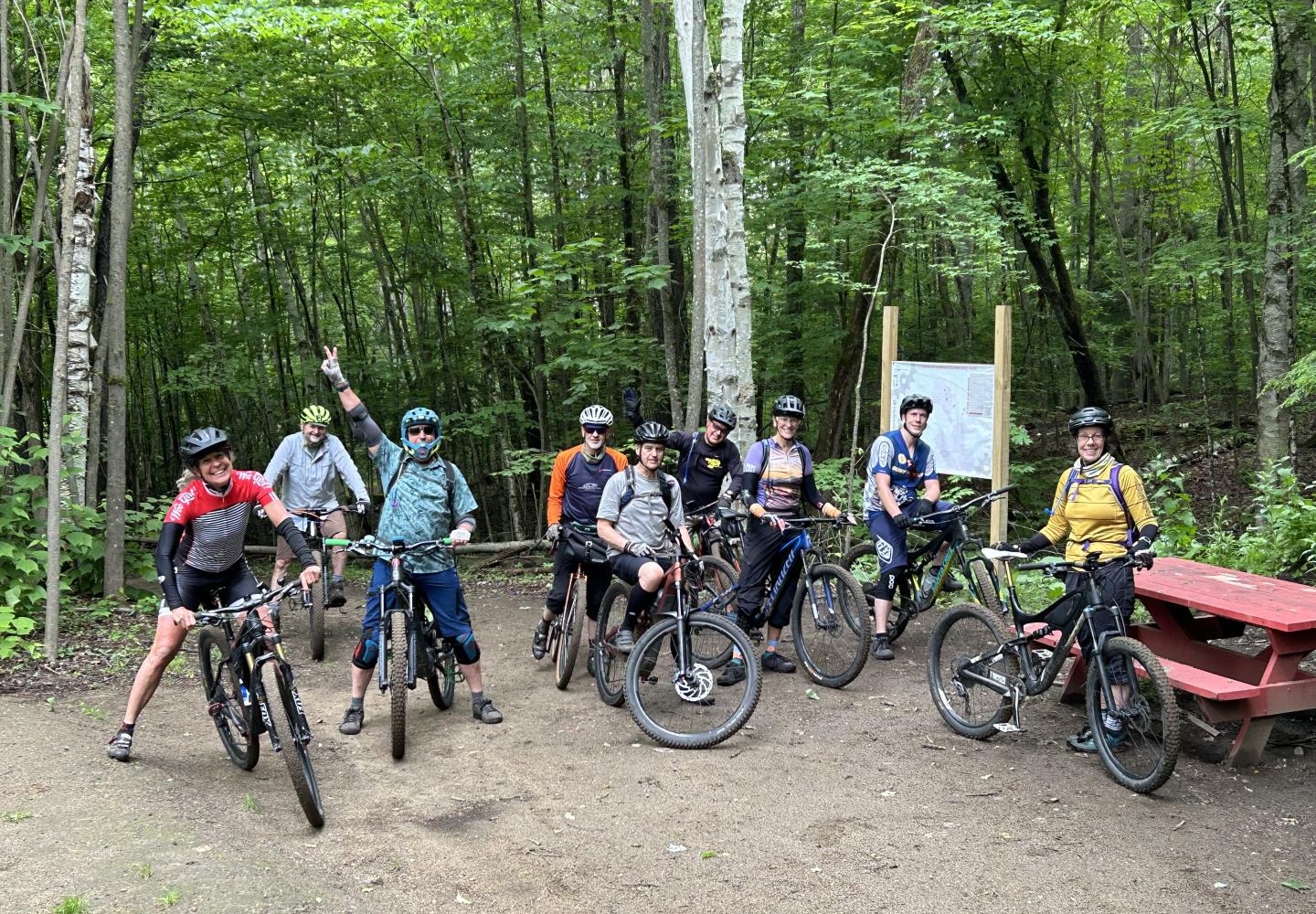 A group of mountain bikers hop off the Adirondack Rail Trail for a stop at the Harrietstown Bike Park featuring a pump track and jump line.