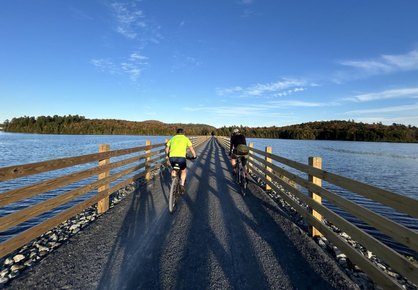 Cyclists ride across the causeway over Lake Colby on the Phase 2 section of the Adirondack Rail Trail.